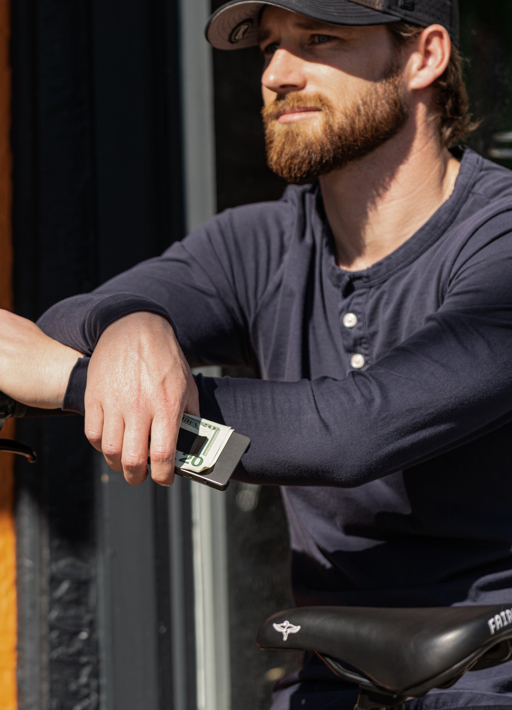 man casually sitting on a bench holding a Groove Life wallet