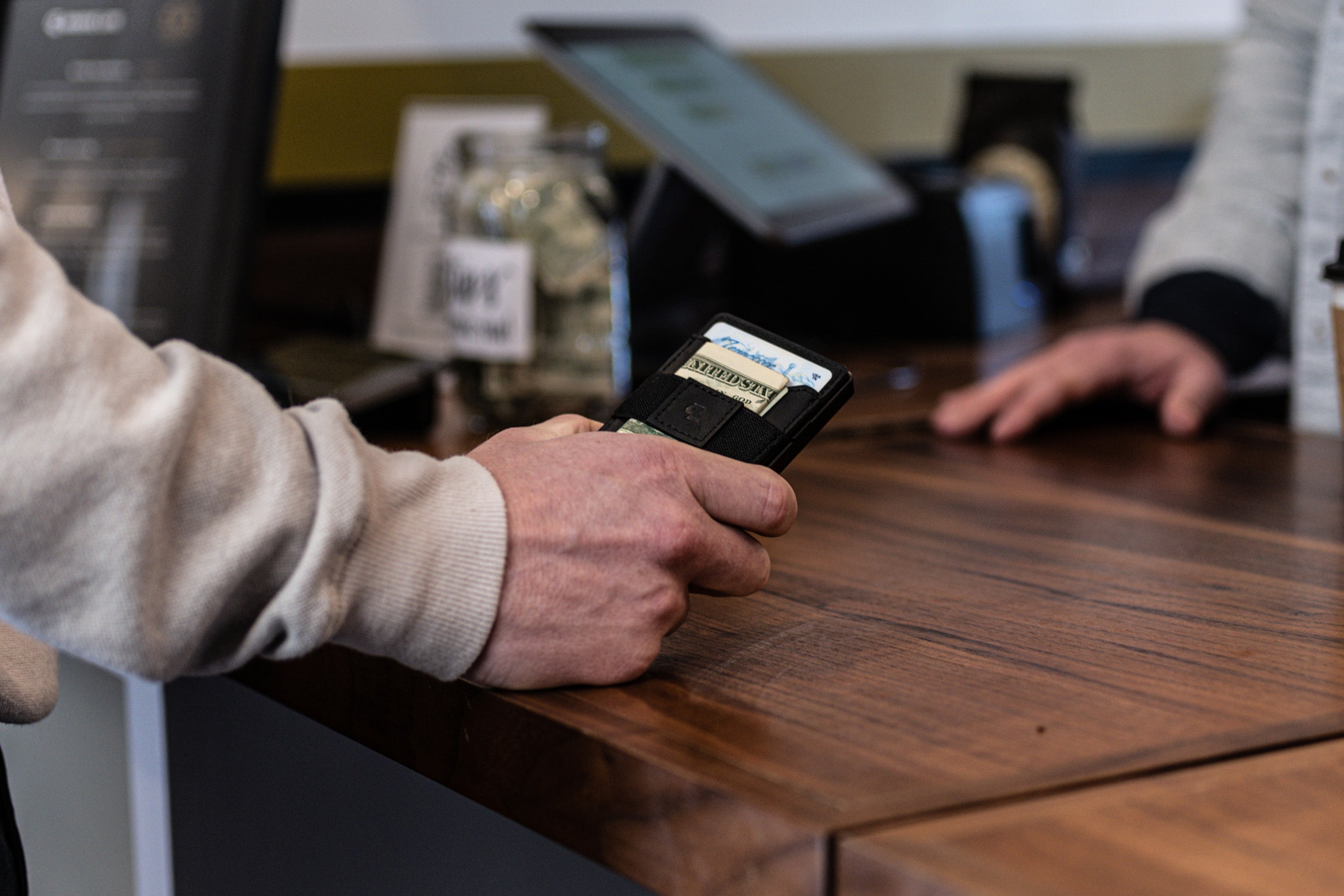 Image of a man holding a Groove Wallet Go with his hand resting on a tabletop