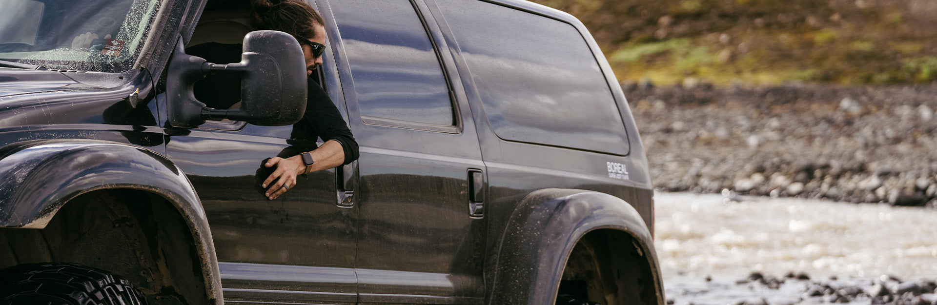 man driving a black SUV with his arm hanging out of the window wearing a Groove Life watch band and ring